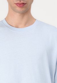 Light blue cotton t-shirt with a crew neckline and short sleeves, featuring a soft texture and simple design without additional patterns.