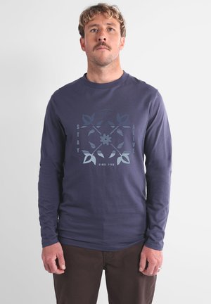Chemise en coton bleu marine à manches longues avec un motif imprimé comportant le texte "STAY ALIVE" et des motifs de feuilles, col rond et coupe régulière.