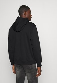 Svart hooded sweatshirt med en mjuk textur, ribbade muddar och fåll, med en klassisk passform och justerbar dragsko i huvan.