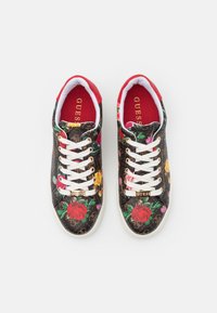 Baskets à imprimé floral noir avec des lacets blancs, des accents rouges et des éléments dorés. Présentent des motifs de roses et de fleurs sur une surface texturée.