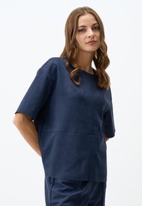 Top navy a maniche corte in morbido materiale simile alla suede, con scollatura rotonda e design senza cuciture con dettagli di cucitura sottili.