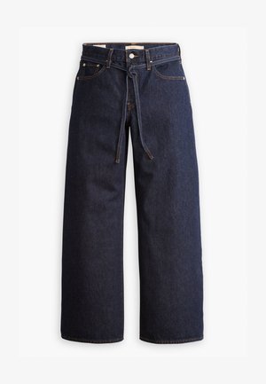 Calças de ganga de perna larga, em azul escuro, com uma cintura alta, apresentando um cordão, cinco bolsos e detalhes de costura em contraste.