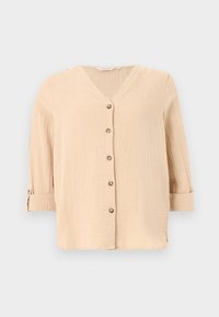 Blouse beige texturée à manches longues avec col en V et cinq boutons devant, manches retroussées et maintenues par une patte à bouton.