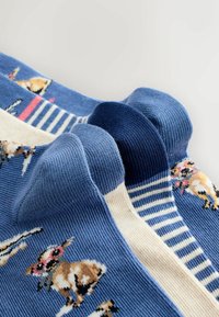 Blauwe sokken met een patroon van honden, voorzien van geribbelde boorden. Eén sok heeft crèmewitte strepen; zachte, gebreide textuur, geschikt voor casual gebruik.