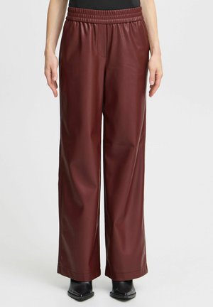 Bordeaux faux leren wijde pijpenbroek met een gestructureerde afwerking, voorzien van een elastische tailleband en zijzakken, gestyled met enkellaarsjes.
