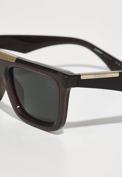 Ochelari de soare Burberry cu rame lucioase, de culoare maro închis și lentile nuanțate de gri. Prezintă un accent auriu pe tâmple, cu detalii ale logo-ului gravat.