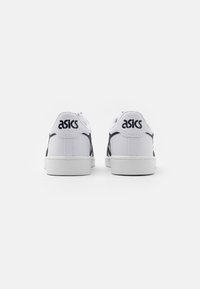 Vita lädersneakers med platt sula. Har svart "asics"-logotyp på hälen och sidan, med minimala färgaccent.