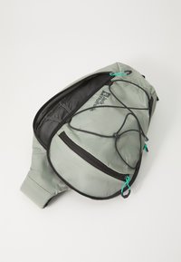 Grå ryggsäck med svarta accenter, dragkedjefack och turkosa draghandtag. Har en elastisk bungee för extra förvaring. Lättviktsmaterial.