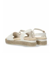 Sandalias blancas con tiras cruzadas, suela de cuerda trenzada beige, tacón redondeado y un pequeño detalle de hebilla metálica en la correa del tobillo.