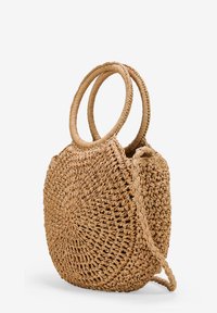 Bolso de paja trenzada de forma circular, con dos asas en bucle y una superficie texturizada en color beige natural. Correa cruzada incluida.