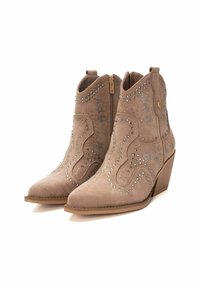 Botas de ante beige hasta el tobillo con puntas afiladas, tachuelas decorativas plateadas en un patrón de estrellas y cierre lateral con cremallera, presentan un tacón apilado.