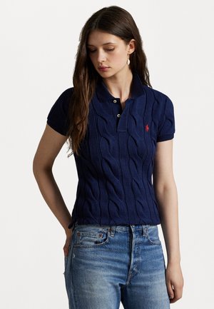 Navyblauwe kabelgebreide polo met een geribbelde kraag en korte mouwen, met een rood logo op de borst en een getailleerd silhouet.