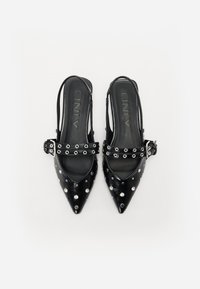 Juodos smailėmis slingback bateliai su sidabro kaiščiais, plačia sagtimi ir glotnia tekstūra. Padas plokščias, su minimaliais dizaino elementais.