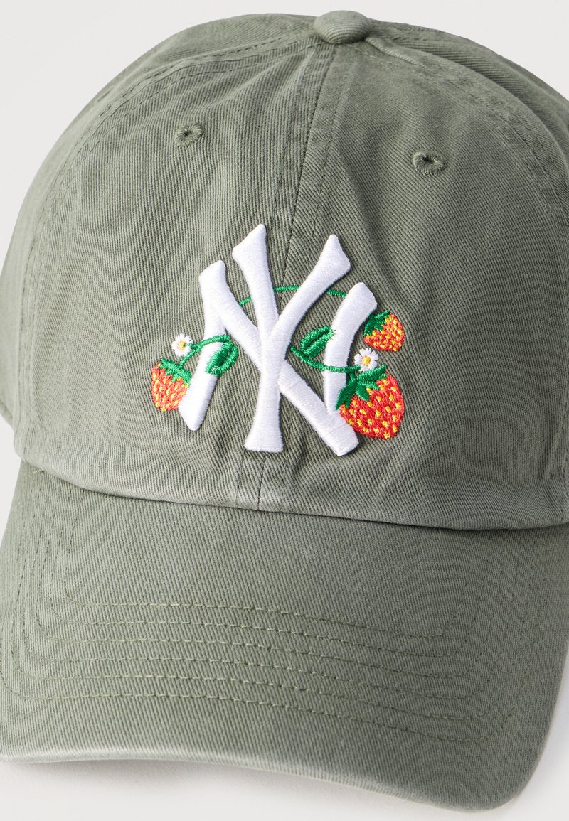 Gorra de béisbol verde oliva con un logo estilizado "NY" en blanco bordado, decorado con fresas bordadas y pequeñas flores blancas.