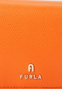 Furla orange textured leather wallet with a rectangular shape, featuring a silver logo accent at the bottom center.