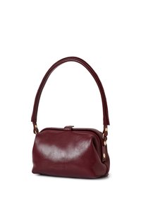 Kleine donkerrode leren handtas met een gebogen bovenhandvat, gouden klinknagels en een drukknoopsluiting op een witte achtergrond.