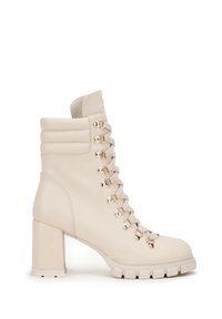Béžová kožená ankle boot s blokovým podpatkem, se stříbrnými očky na šněrování, polstrovaným límcem a texturovanou podrážkou s drážkami.