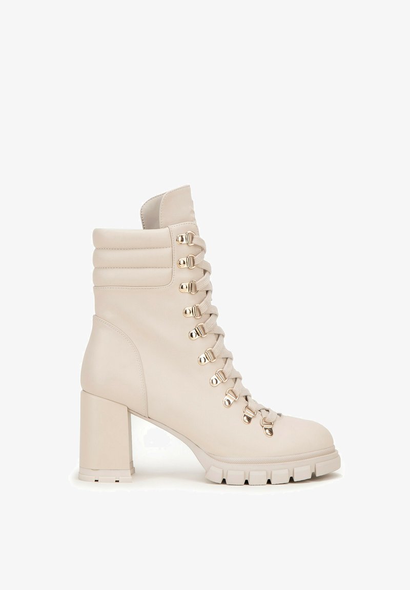 Beżowe skórzane botki za kostkę na słupku, z metalowymi hakami na sznurówki, wyściełanym kołnierzem oraz fakturowaną podeszwą z rowkami.