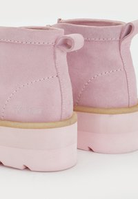 Ρόζ σουέτ μποτάκια ankle με κοντό μολύβι, που διαθέτουν υφή, διπλά κορδόνια και χοντρές ροζ καουτσούκ σόλες. Λογότυπο ορατό στο πλάι.