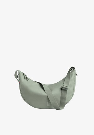 Sac bandoulière gris clair en forme de croissant avec une sangle ajustable et une fermeture éclair supérieure, doté d'une petite étiquette en tissu sur le côté.