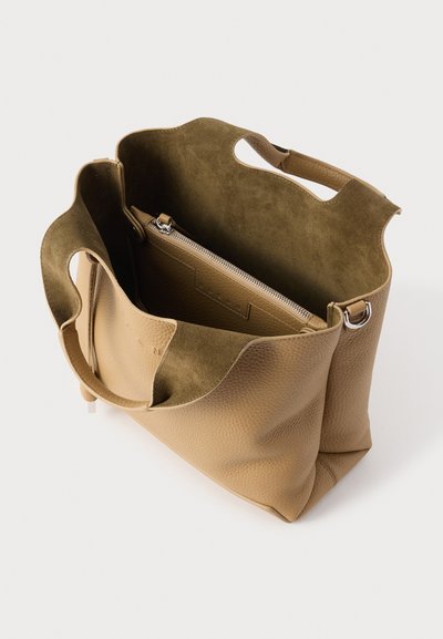 Brązowa torba typu tote ze skórzaną, fakturowaną powierzchnią i miękką podszewką z zamszu. Posiada podwójne uchwyty oraz zamykaną na suwak kieszeń wewnętrzną.