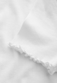 Weißer Baumwollstoff mit feinen vertikalen Streifen und einem gekräuselten Rand, der eine glatte Textur und ein weiches Aussehen zeigt.