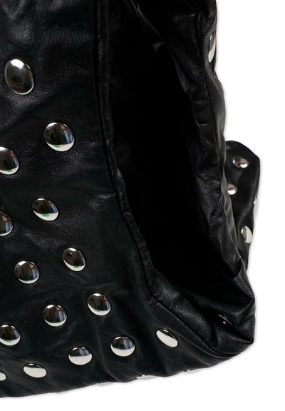 Zwarte leren tas met metalen studs. De tas heeft een zachte textuur en een slouchy ontwerp, met een open interieur zonder zichtbare compartimenten.