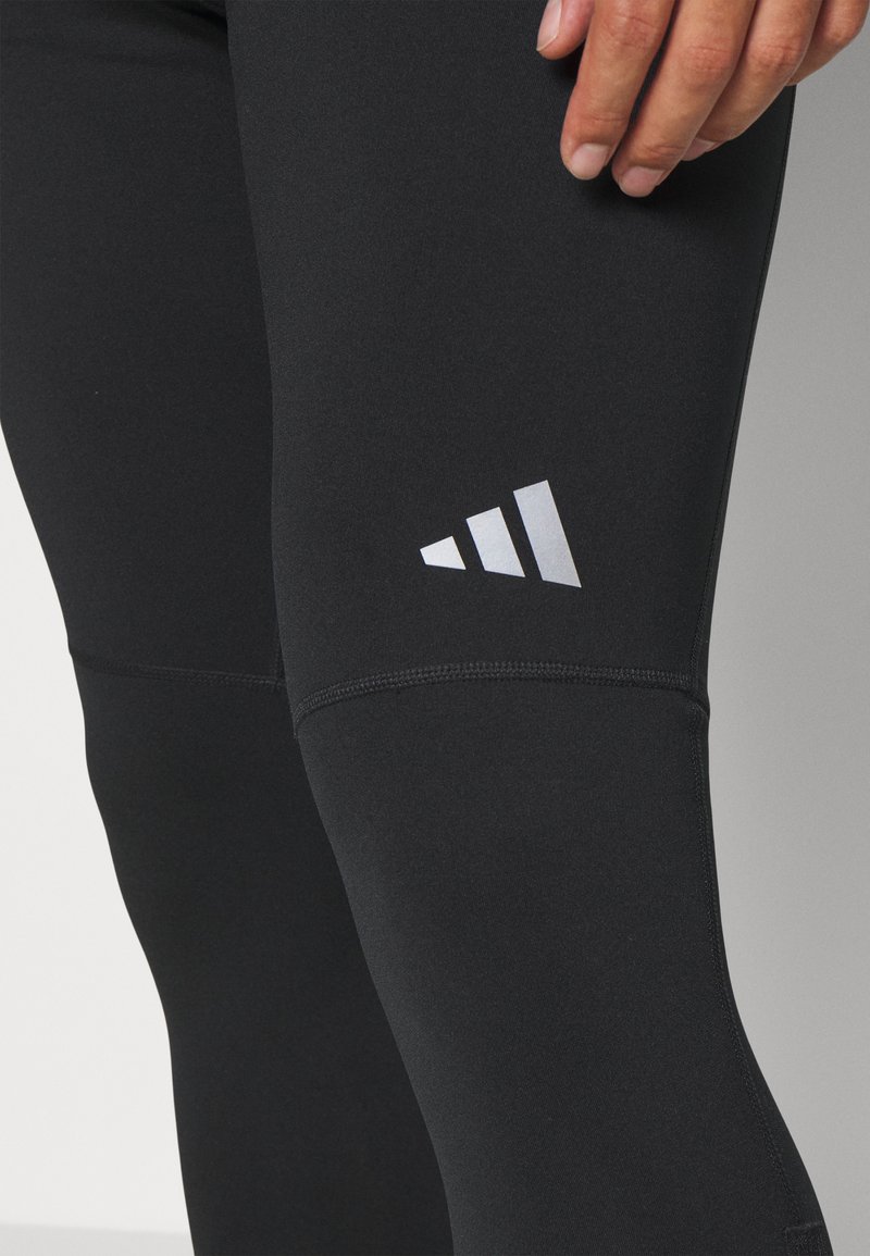 Zwarte sportleggingen van rekbaar materiaal. Heeft een wit logo op de dij en platgestikte naden voor duurzaamheid.