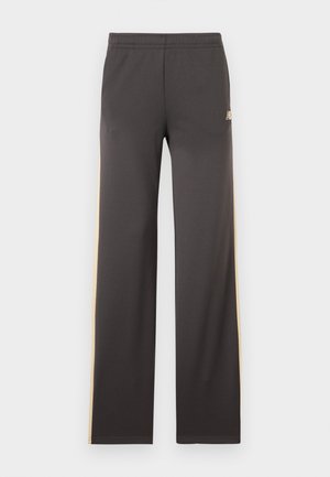 Tamsiai pilkos sportinės kelnės su smėlio spalvos šoninėmis juostelėmis ir elastine juosmens juosta, atvaizduotos ištiestos ant balto fono.