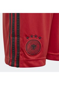 Czerwone sportowe szorty wykonane z materiału syntetycznego. Posiadają czarne boczne paski oraz czarne haftowane logo z pięcioma gwiazdkami.