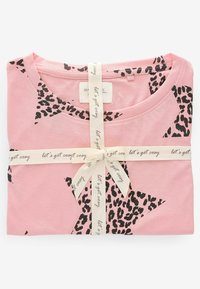 Lyserød bomulds T-shirt med sorte leopardprint-stjerner, foldet pænt og bundet med et kremfarvet bånd, der står "lad os blive hyggelige".