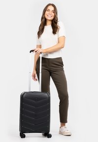 Černý kufr na kolečkách s vzorem kosočtverce, tvrdá skořepina, nastavitelné madlo a čtyři kola. Vyznačuje se svým elegantním, moderním designem.