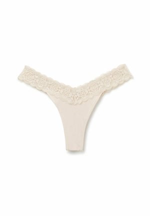 Beige tanga ondergoed met kanten rand, bloemenpatronen in de tailleband, een gladde stof en een V-vormig ontwerp aan de voorkant.