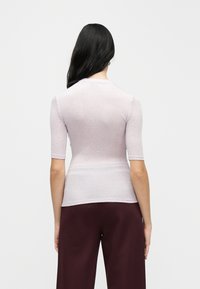 Ανοιχτό μωβ εφαρμοστό τ οπ με κοντά μανίκια, κατασκευασμένο από λείο, ελαστικό ύφασμα. Ο σχεδιασμός περιλαμβάνει λαιμόκοψη τύπου πλοιάρχου και αδιάκοπη τελική ραφή.