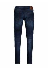 Mörkblå denimjeans med slim fit, prydda med en brun läderlapp i midjan, fem fickor och en diskret blekning längs benen.
