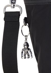 Borsa nera in nylon con cinturino testurizzato e hardware metallico argentato, decorata con un lucido portachiavi metallico a forma di piccolo robot.