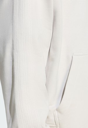 Jasnoszara bluza z kapturem z teksturowanymi paskami po bokach, kieszenią z przodu i miękkim materiałem. Szwy dodają subtelnego wizualnego zainteresowania.