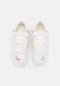 Białe sneakersy mają gładką skórzaną powierzchnię z różowymi, żółtymi i fioletowymi akcentami w kształcie serc. Sznurowany krój i oksydowane oczka w kolorze złotym.