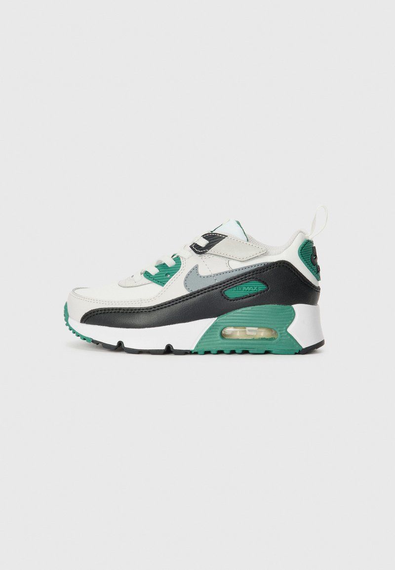 Fehér és fekete sneaker zöld kiegészítőkkel, hálós és bőrből készült felső résszel, párnázott bokarésszel, valamint látható légkamrával a sarkában.