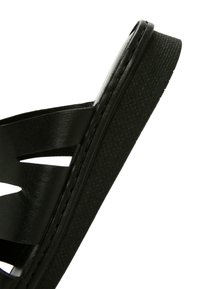 Sandal nero con suola testurizzata, lati aperti con design a intaglio e tomaia in pelle liscia. Struttura solida con cuciture minime.