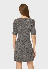 Vestido de manga corta con un patrón abstracto en negro, blanco y rojo, cintura ajustada y textura suave, que llega hasta la mitad del muslo.