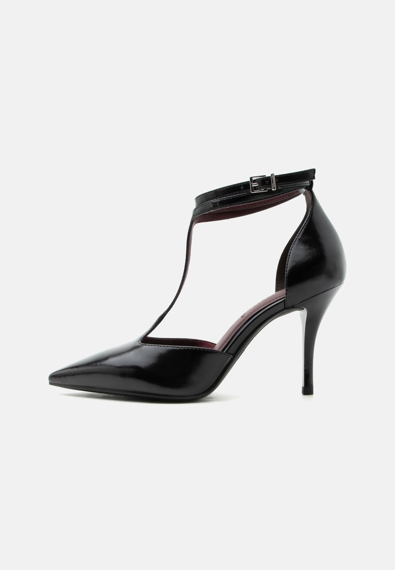 Chaussure à talon haut en cuir verni noir à bout pointu avec bride en T et fermeture à boucle autour de la cheville.