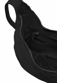 Borsa in tessuto nero con chiusura a zip, caratterizzata da una texture liscia, una tasca interna e una tracolla curvata. L'interno è ordinato.