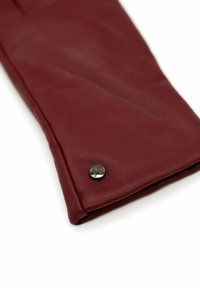 Burgundy leather glove with a smooth texture, featuring a metal snap button accent with a logo. Folded design shows inner lining.