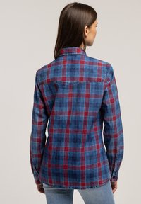 Koszula z długim rękawem w niebiesko-czerwony kratkowany wzór, wykonana z miękkiego materiału, z ostrogowym kołnierzykiem i subtelnym detalem na plecach.
