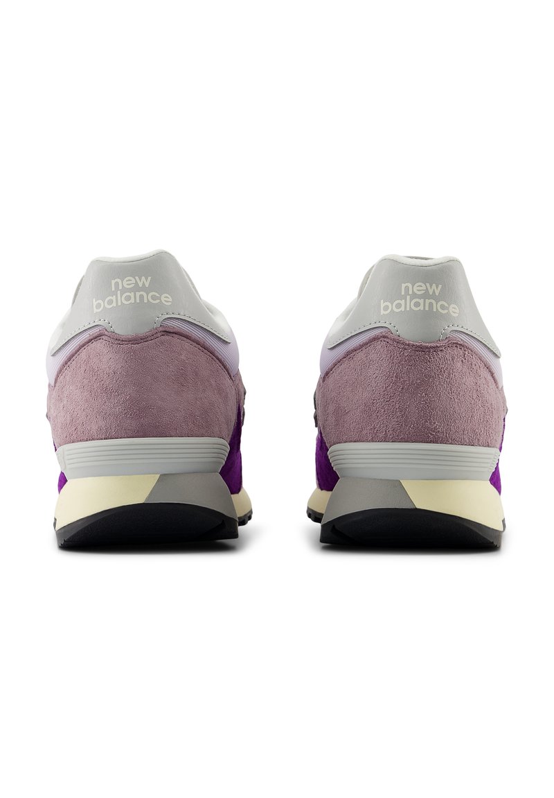 Zapatillas New Balance con parte superior de ante en tonos morado y rosa, detalles grises y una lengüeta trasera blanca con el logo, sobre una suela en crema y negro.