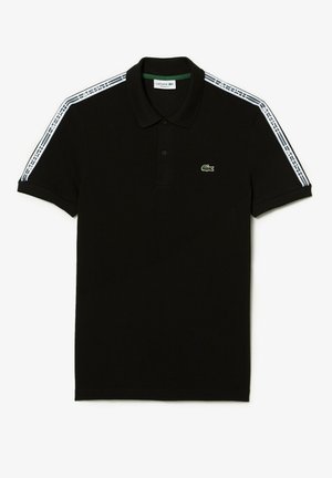 Schwarzes Polo mit kurzen Ärmeln und weißem "Lacoste"-Band entlang der Schultern und Ärmel, mit grünem Krokodil-Logo auf der linken Brust.