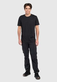 Zwarte korte mouwen t-shirt gecombineerd met zwarte cargobroek en zwarte sneakers. De outfit heeft een relaxte pasvorm en duurzame stof.