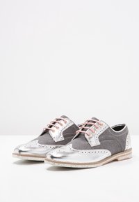 Oxfords en tissu gris avec des accents en cuir argent, des lacets roses, des détails brogue et une semelle texturée. Bout arrondi avec des matériaux contrastants.