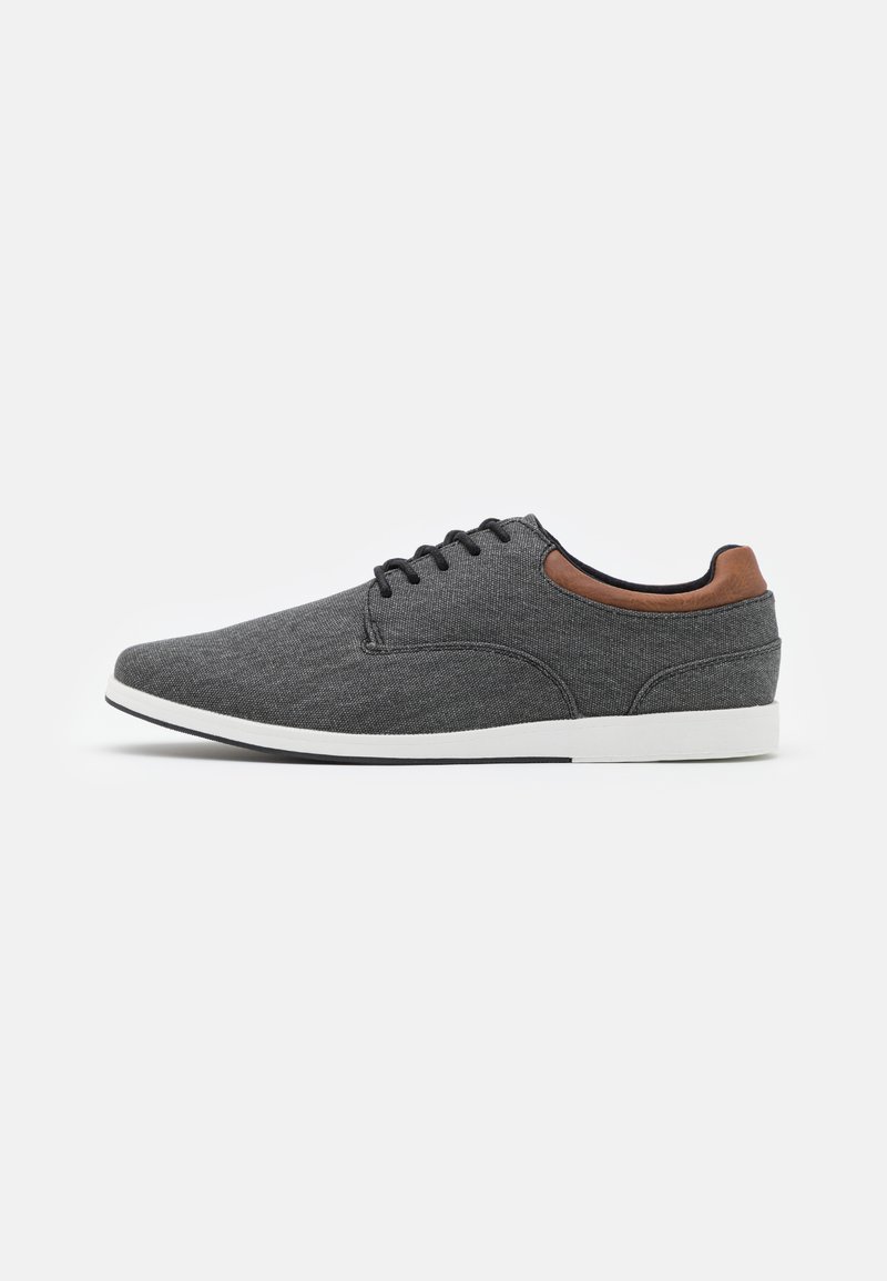 Grijze stoffen schoenen met een gladde textuur, een bruine leren accent bij de hak en een witte rubberen zool. Vetersluiting, slank silhouet.
